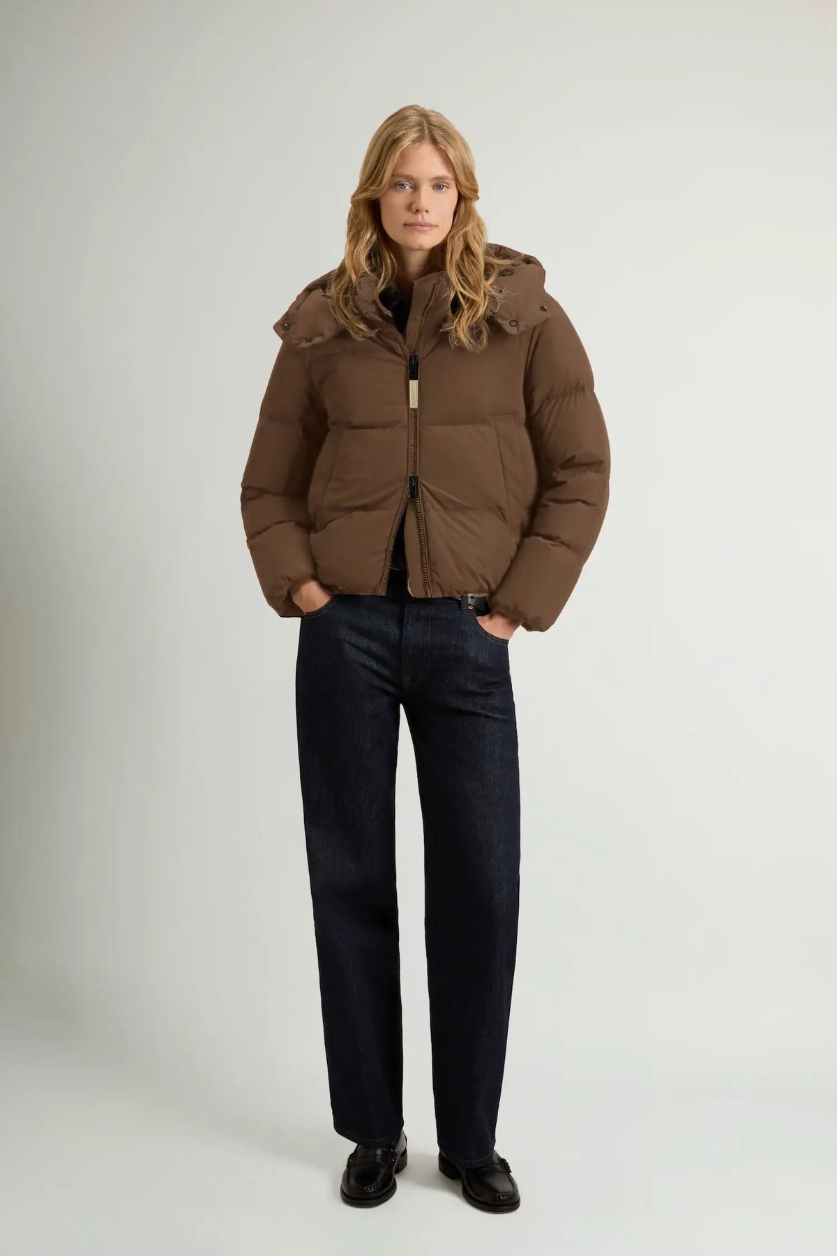 Model wearing Madison Jacket Dark Earth Coat by Woolrich, featuring a removable hood and windproof design.
