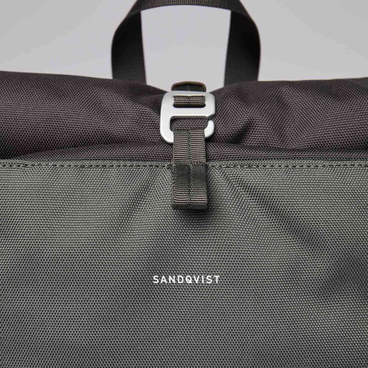 Arvid Multi Green Backpack roll-top closure with metal hooks and Sandqvist branding detail.
