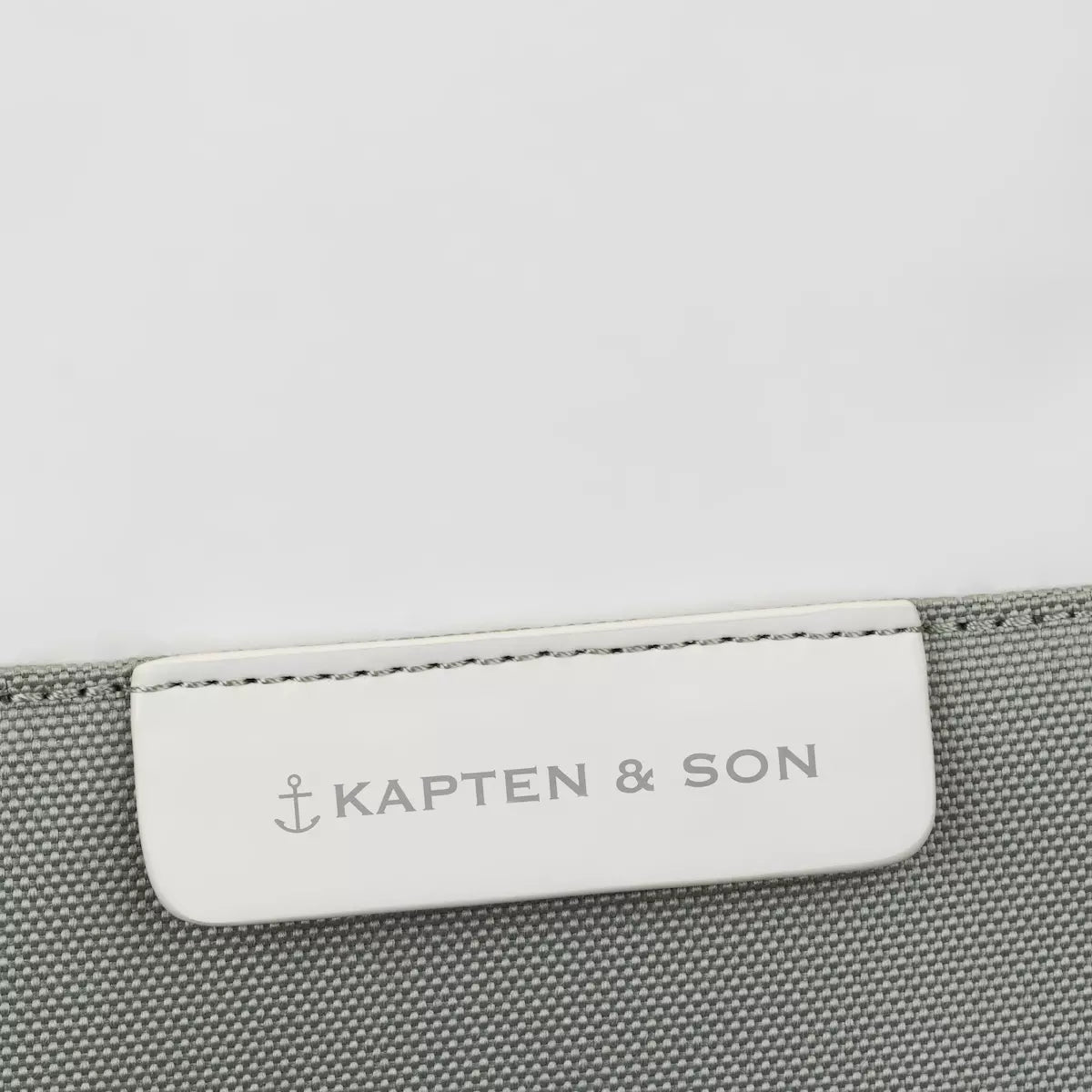 Label of Kapten & Son brand on a muted sage backpack for style and quality assurance.