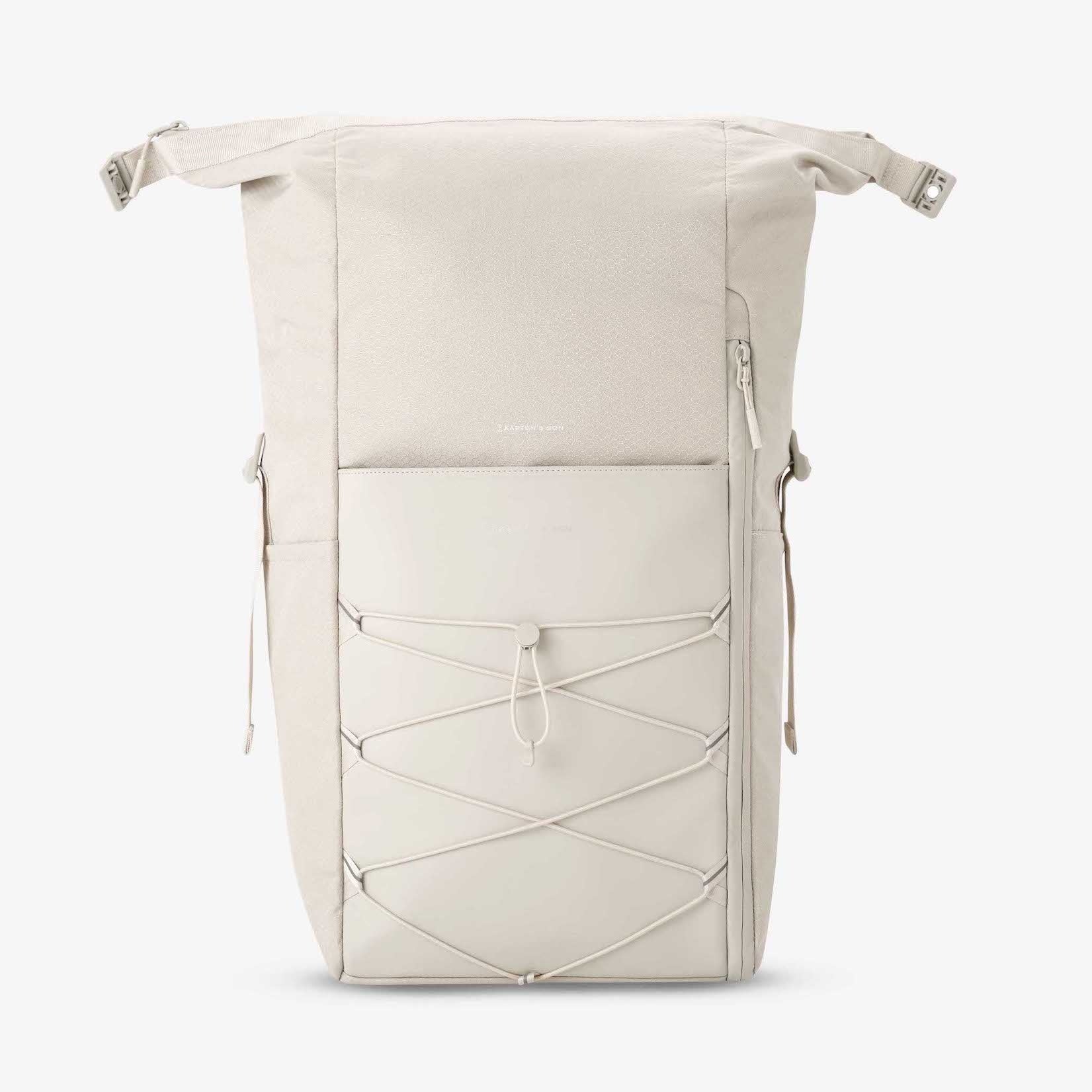 Yoho Sandstone Backpack in a light color with magnetic buckles and zipper closure, featuring side pockets and padded straps.