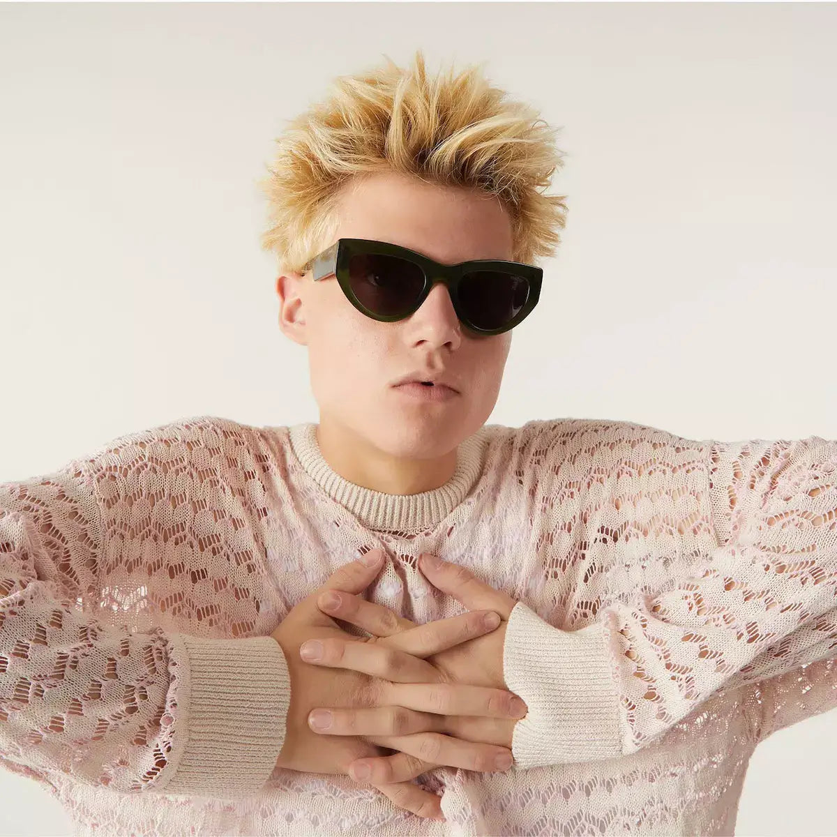 Person wearing Kim Seaweed Sunglasses with dark purple lenses and a stylish pink sweater.