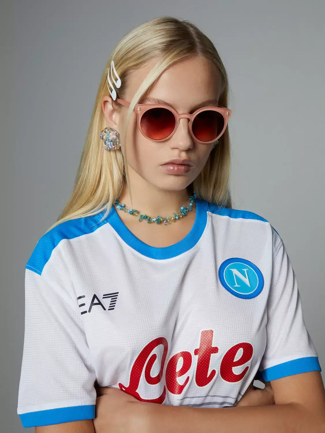 Lulu Velvet Coral Sunglasses worn by a model with a white Napoli jersey and accessories, featuring cat eye design.