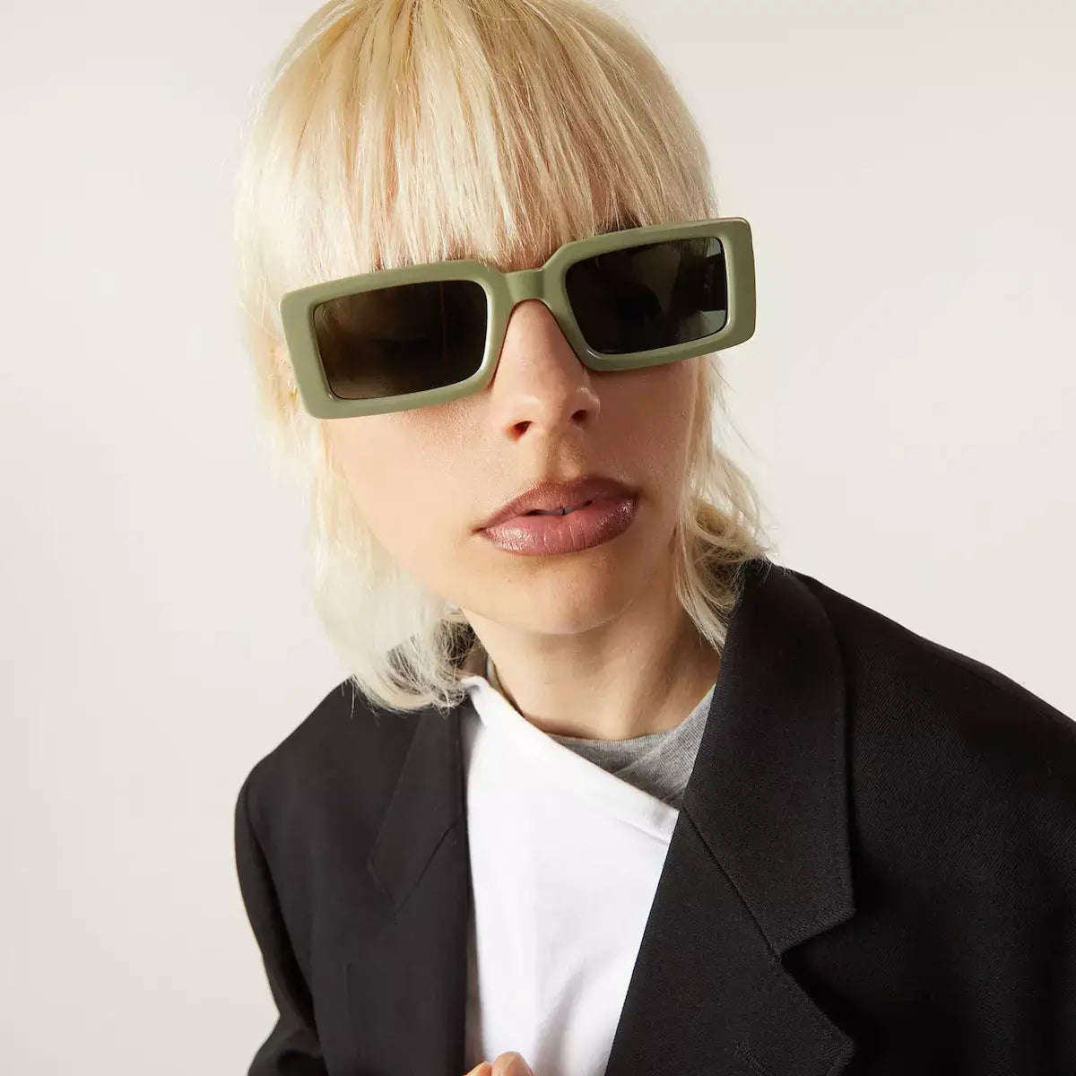 Malick Moss Sunglasses on model with blonde hair wearing a black blazer and solid green lenses.