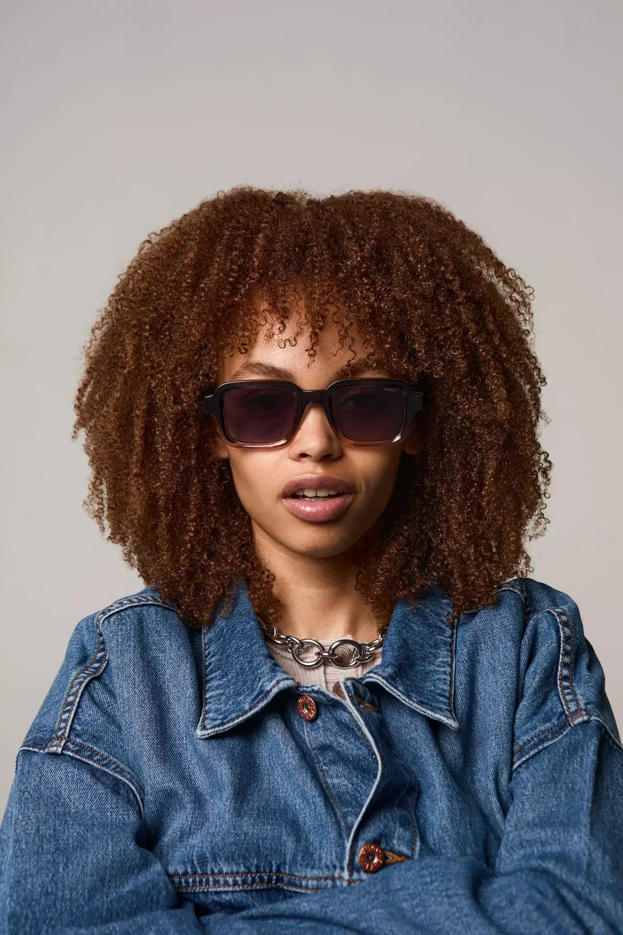 Lionel Atlantic Sunset Sunglasses model wearing stylish eyewear with curly hair and denim jacket.
