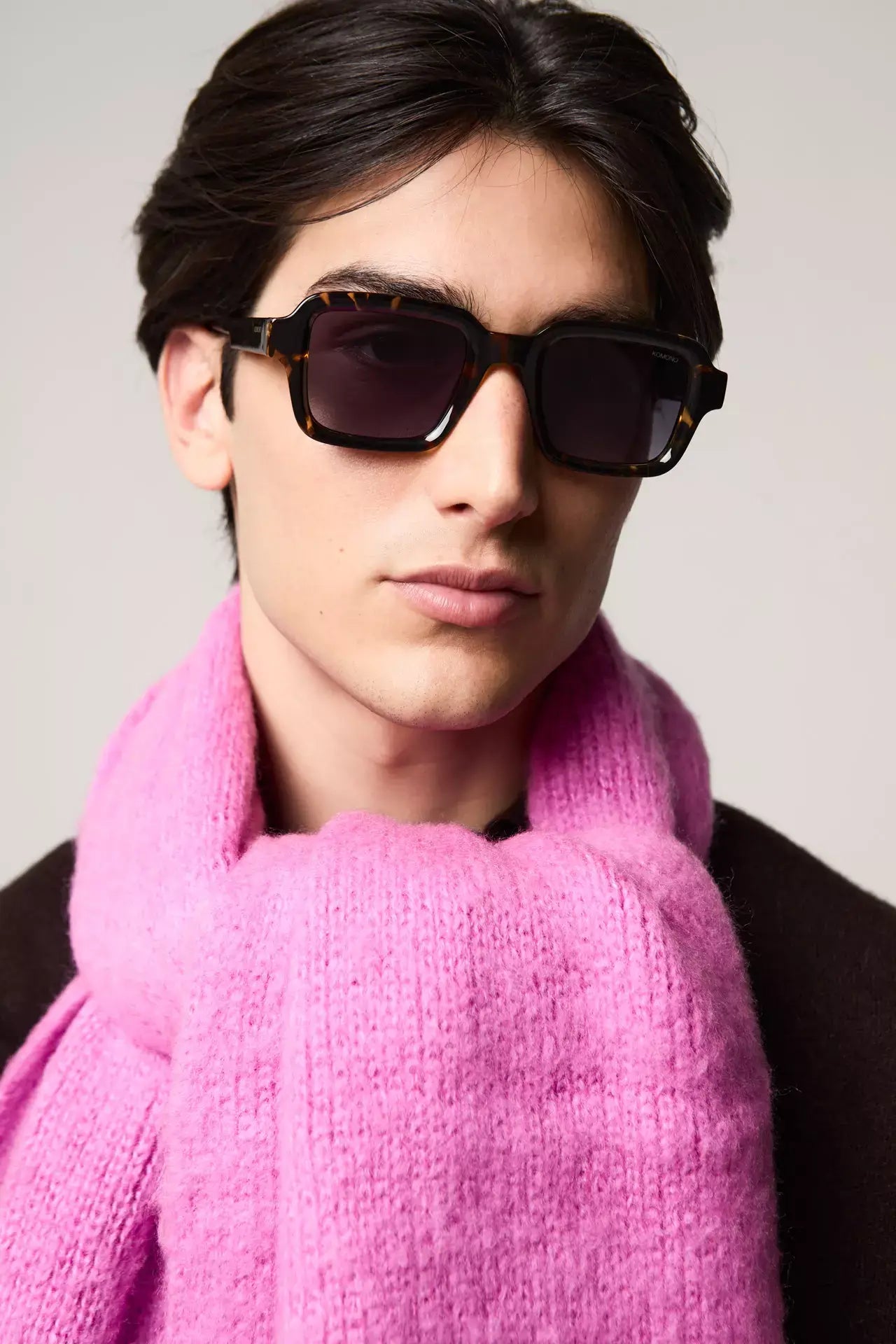 Lionel Dark Tortoise Sunglasses modeled by a young man wearing a pink scarf, showcasing UV protection and eco-friendly design.