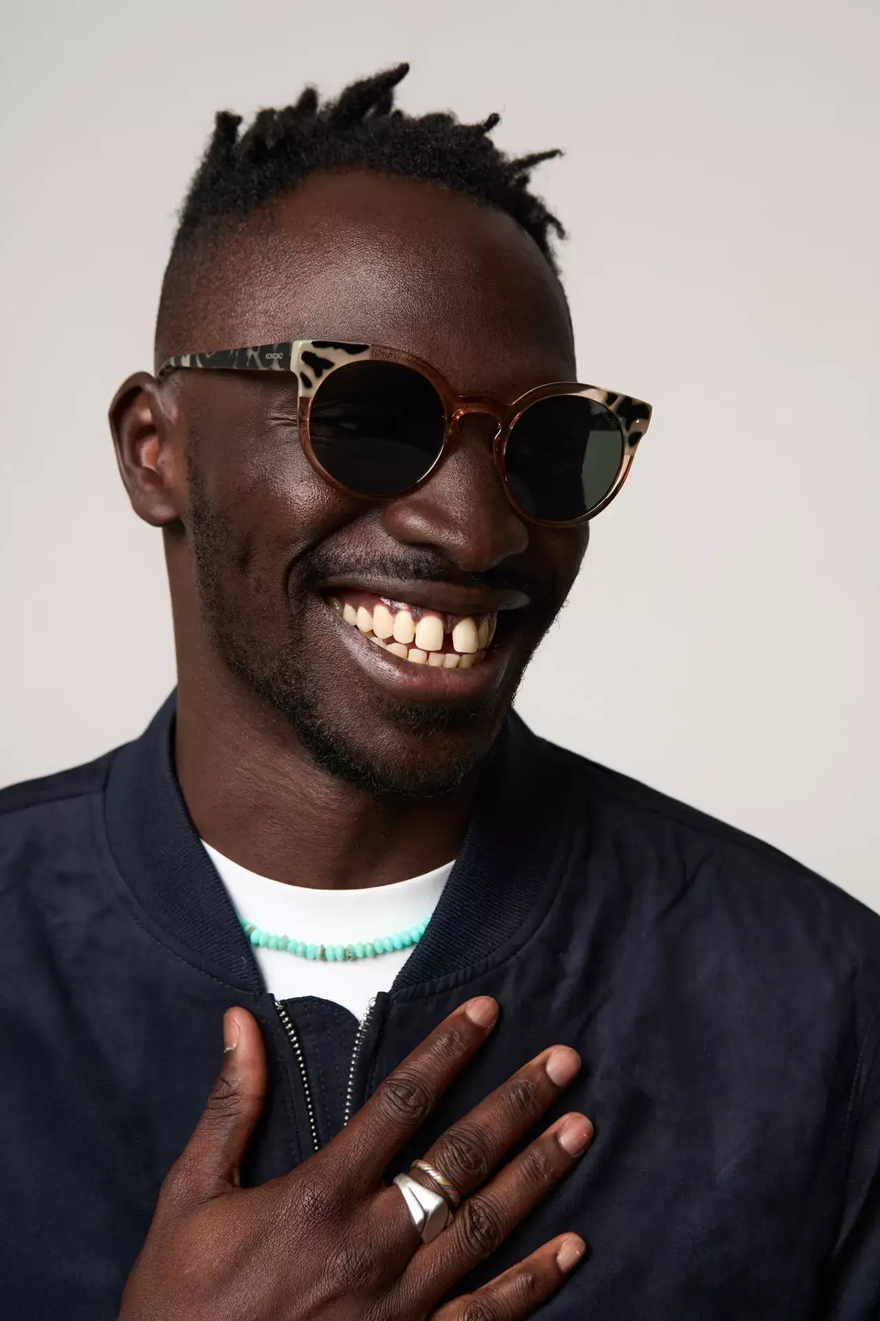 Man wearing Lulu Coral Bobcoat Sunglasses with cat eye design and eco-friendly bio nylon frame, smiling.