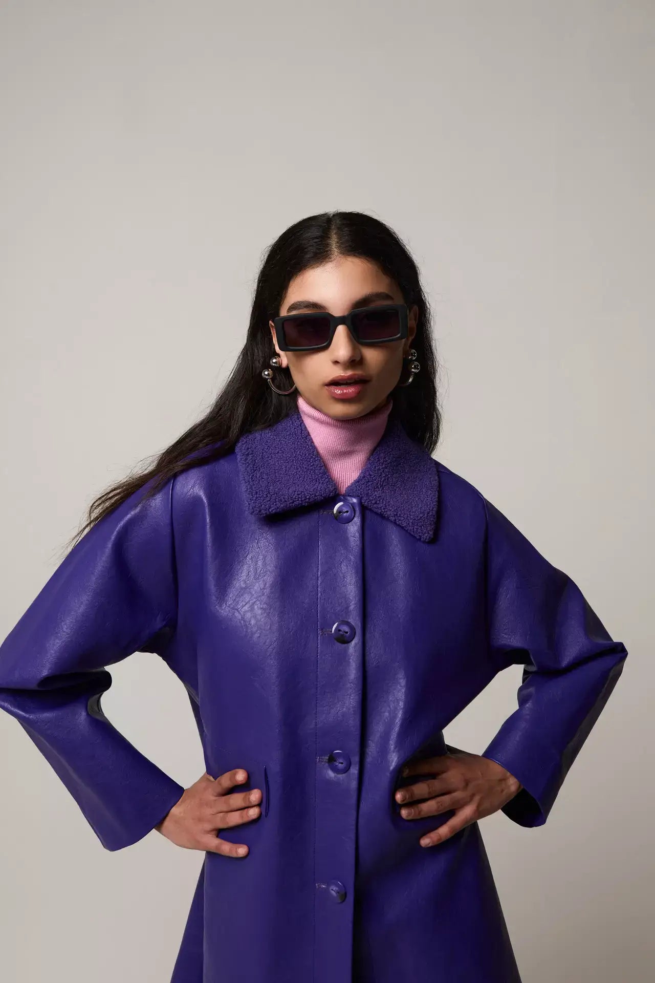 Model wearing Malick Carbon Sunglasses with a purple coat and pink turtleneck fashion ensemble.