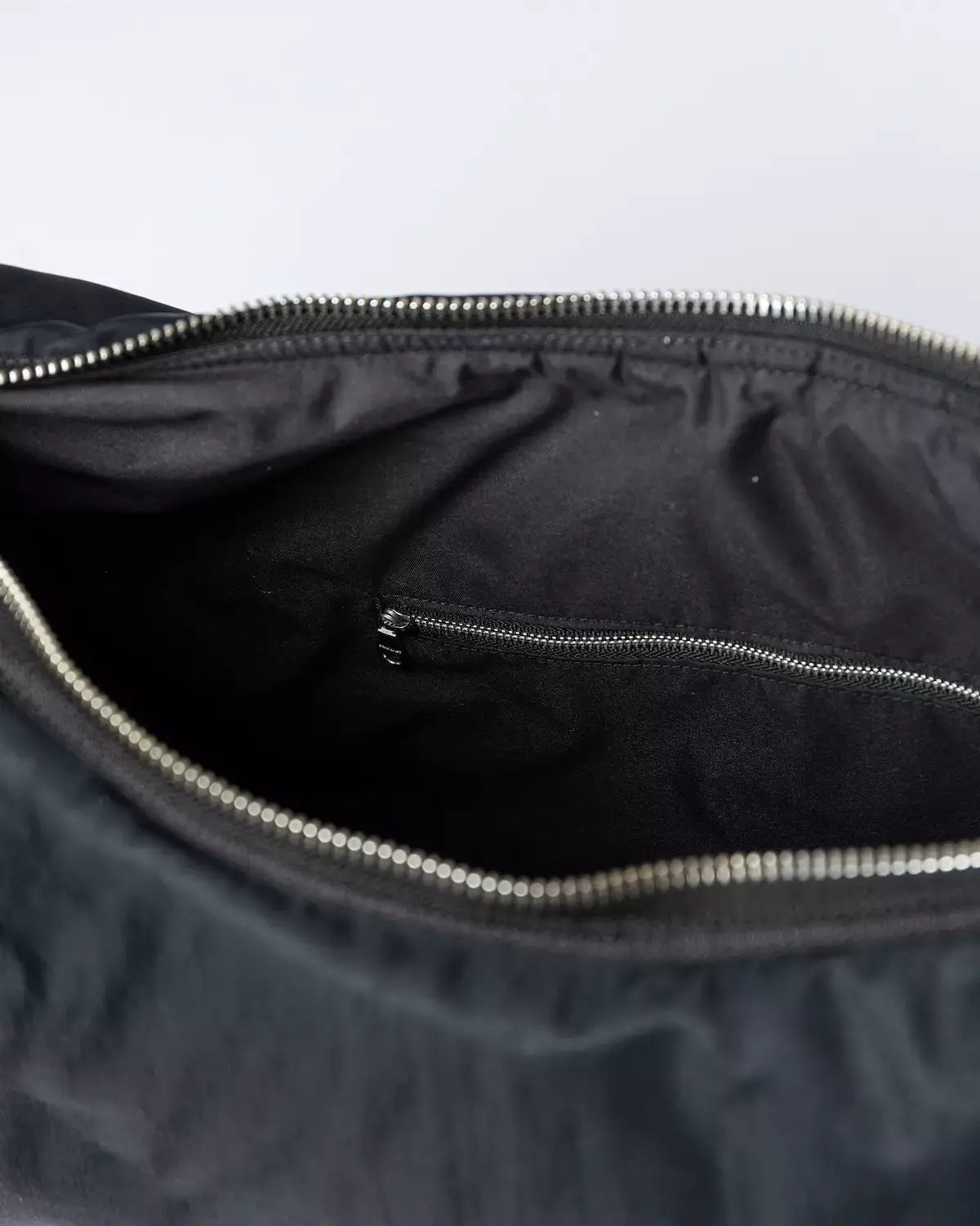 Interior view of the Curve Crossbody Round L Black Shoulder Bag showing the internal zipper pocket for organization.