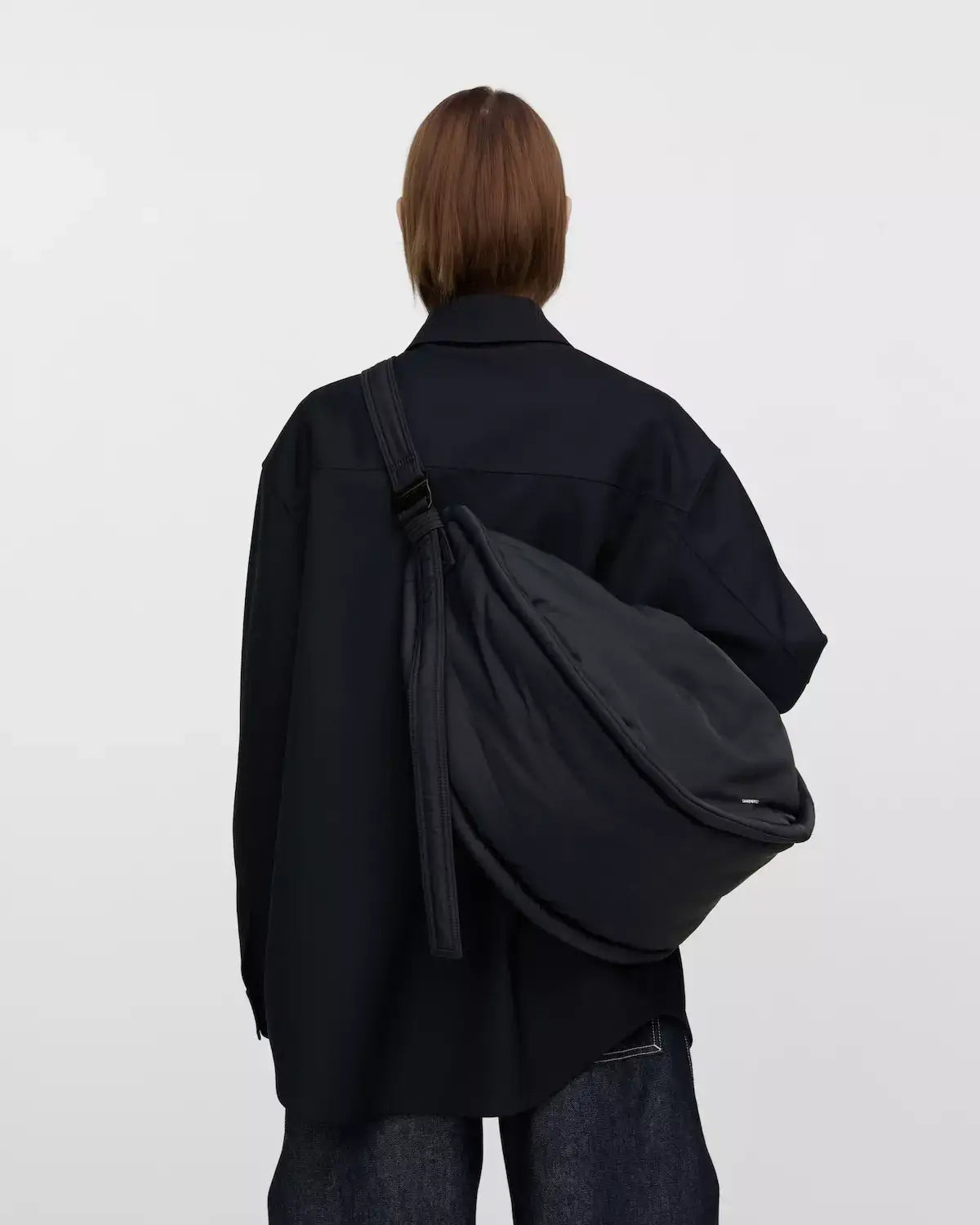 Person wearing a Curve Crossbody Round L Black Shoulder Bag, showcasing its design and functionality.