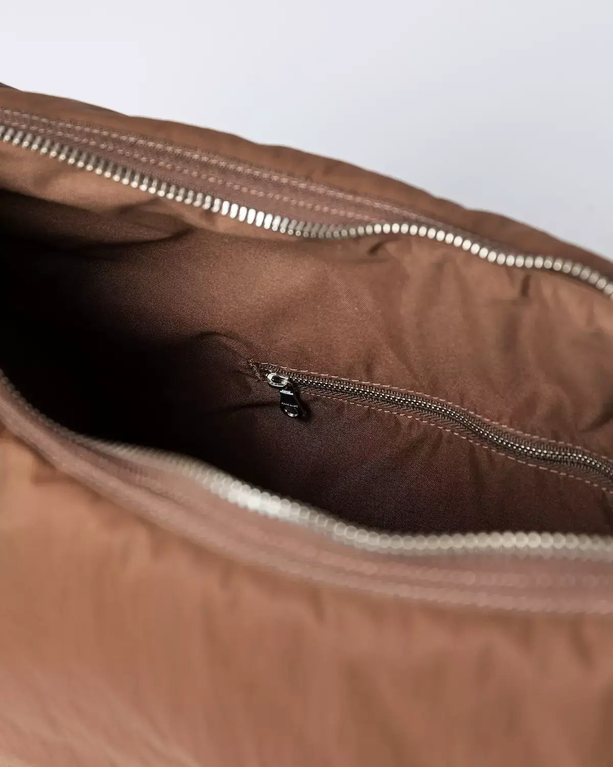 Interior view of the Curve Crossbody Round L Dark Taupe Shoulder Bag featuring a zipper pocket.