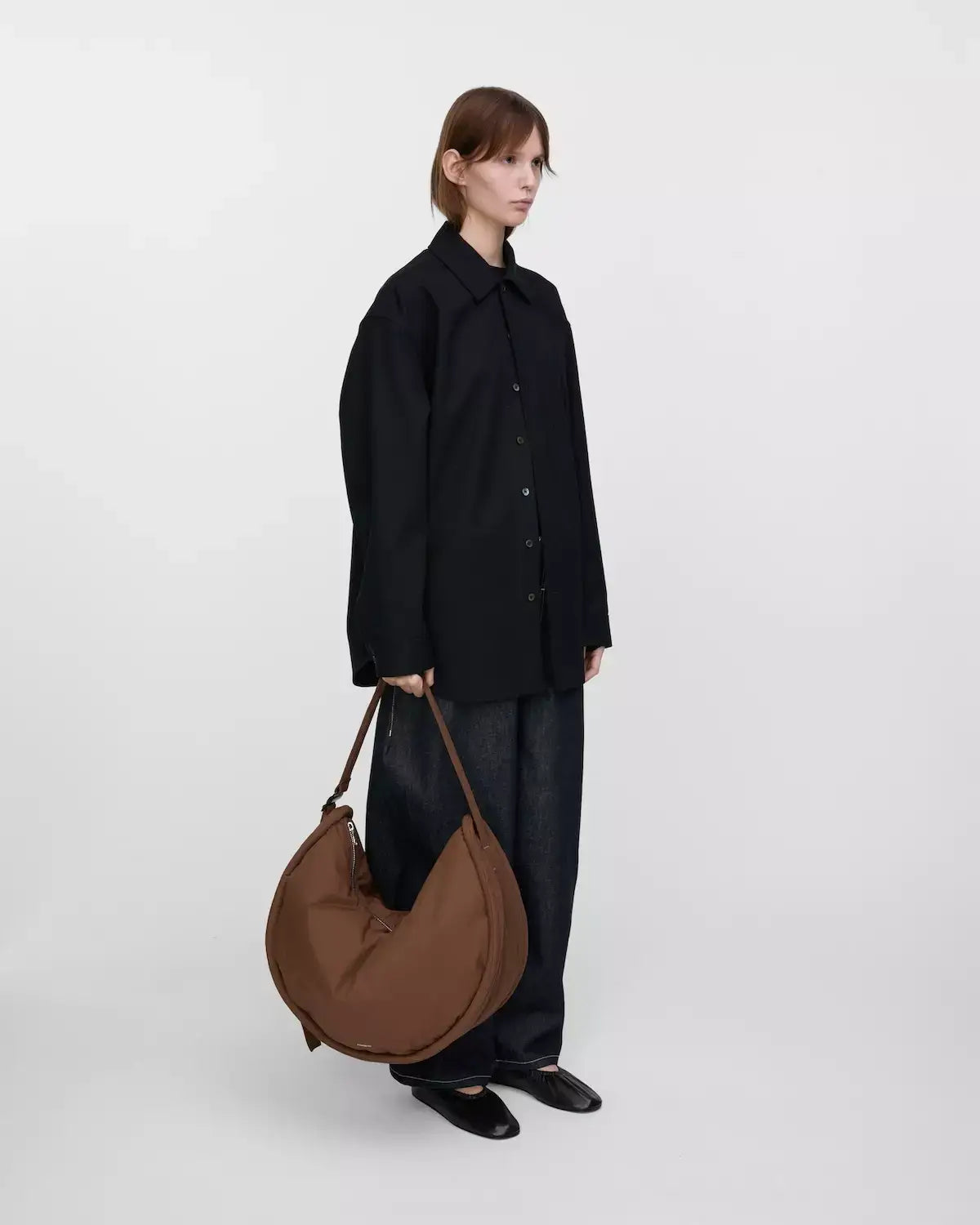 Model carrying Curve Crossbody Round L Dark Taupe Shoulder Bag, showcasing style and functionality.