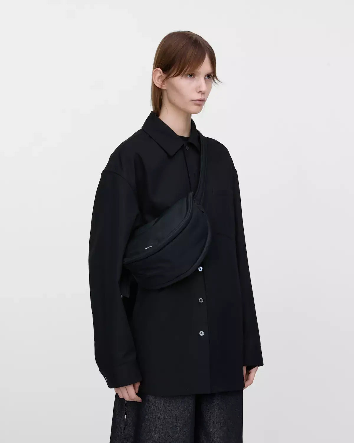 Model wearing Curve Crossbody Round S Black Shoulder Bag, showcasing its sleek design and versatility.