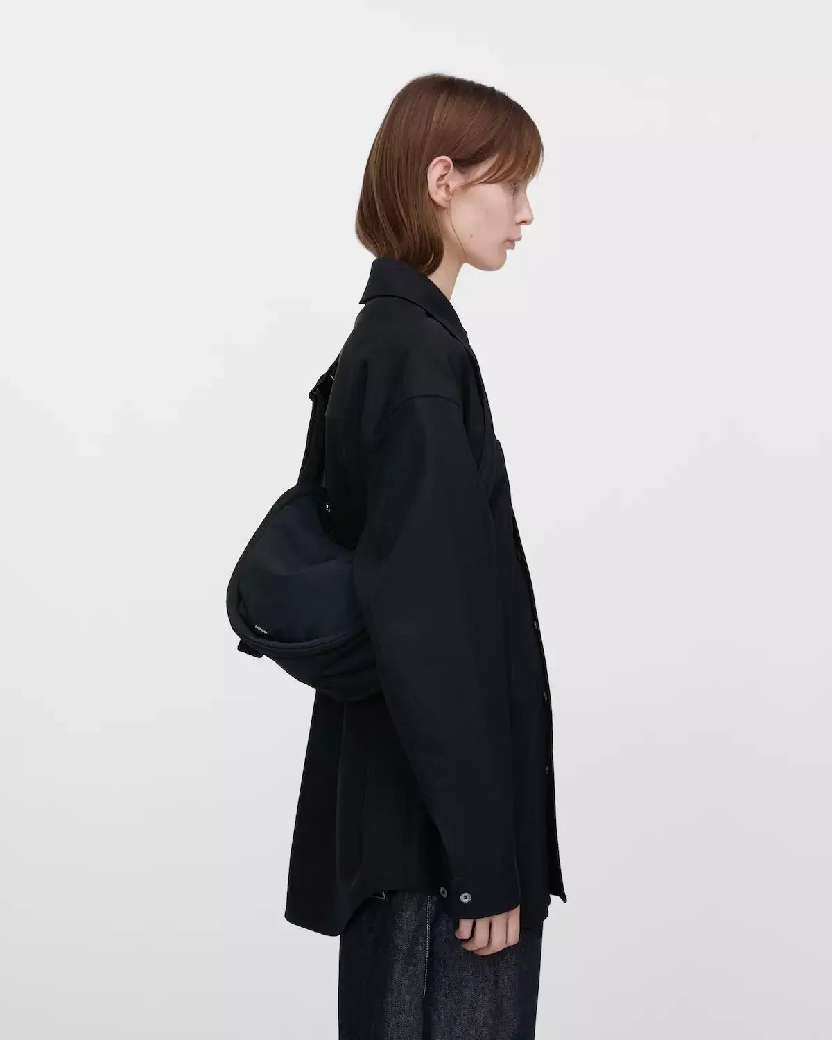 Model demonstrating the Curve Crossbody Round S Black Shoulder Bag, showcasing its lightweight and stylish design.