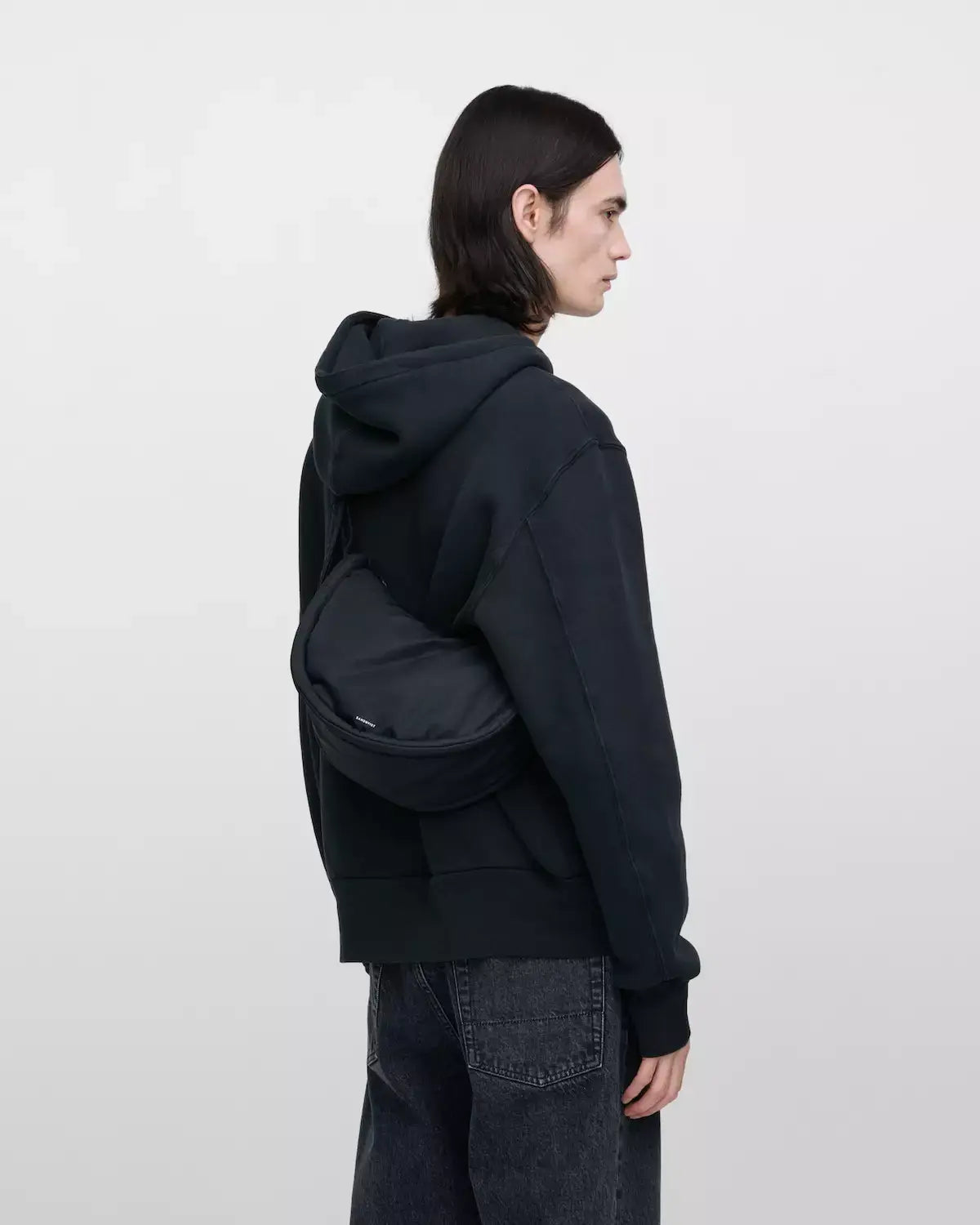 Model wearing a Curve Crossbody Round S Black Shoulder Bag over the shoulder with a casual outfit.