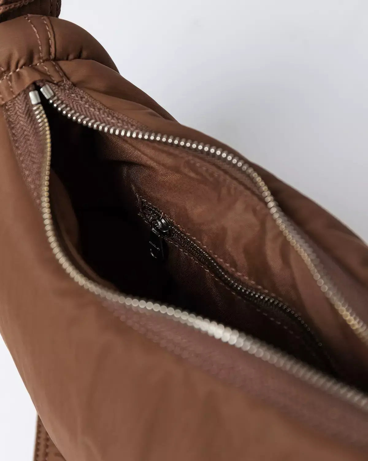 Inside view of the Curve Crossbody Round S Dark Taupe Shoulder Bag showing zipper pocket and lining.