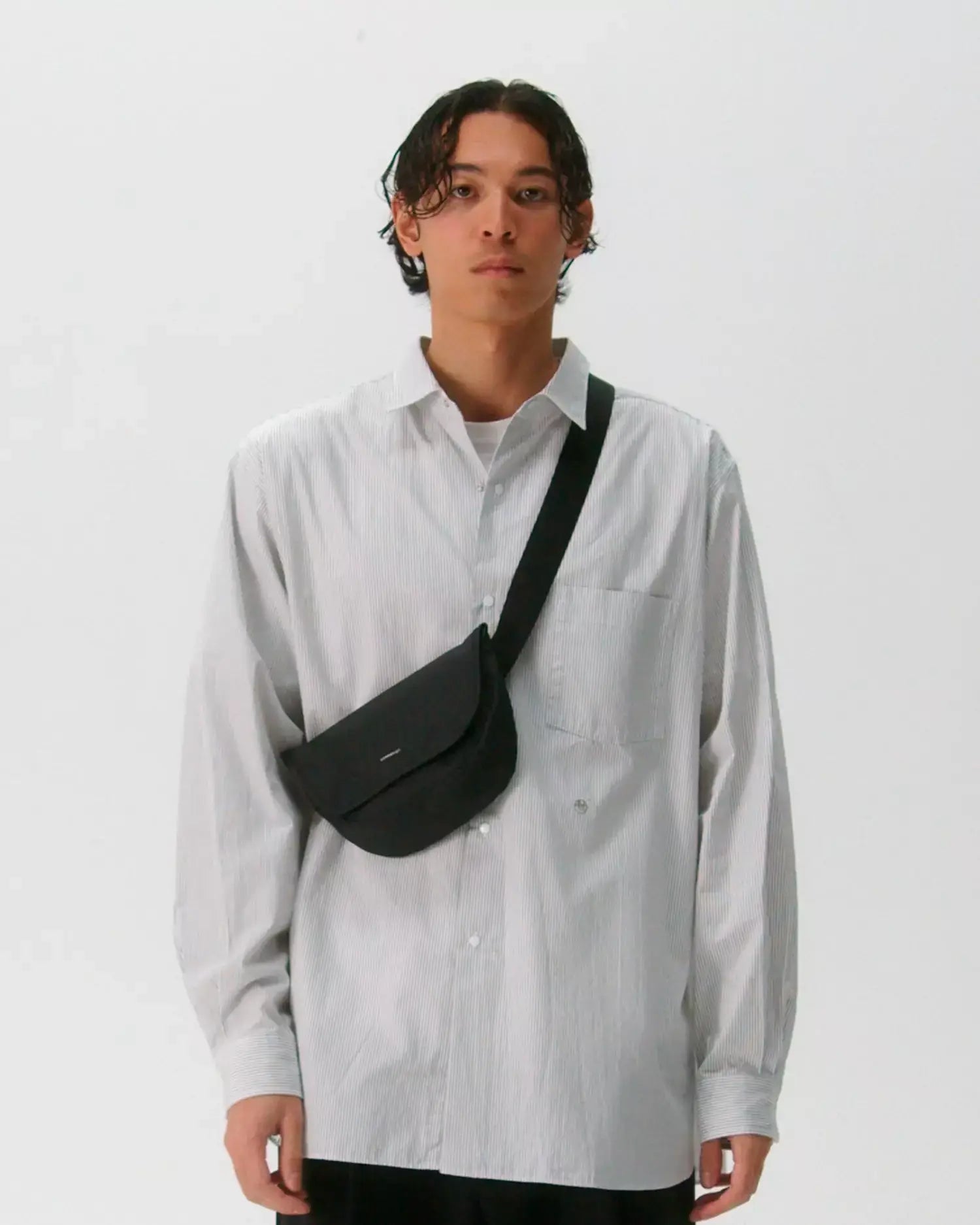 Model wearing Stream Messenger Mini Black Shoulder Bag across the body with a casual outfit.