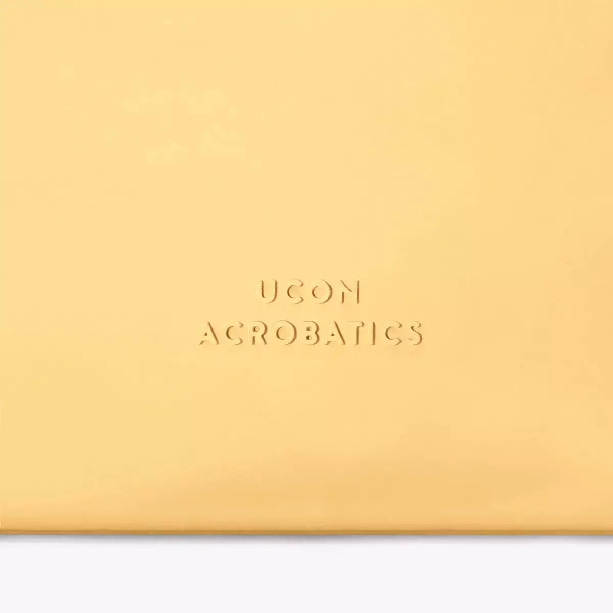 Alva Medium Lotus Infinity Lemon Shoulder Bag with UCON Acrobatics branding on a smooth yellow surface.