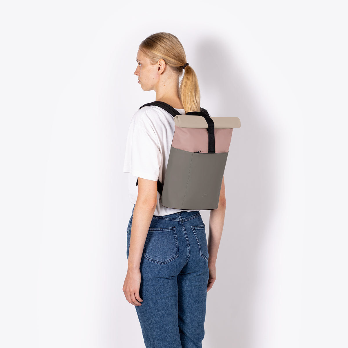 Hajo Macro Lotus Rose Dark Grey Backpack being worn by a model, showcasing the roll-top and padded straps.