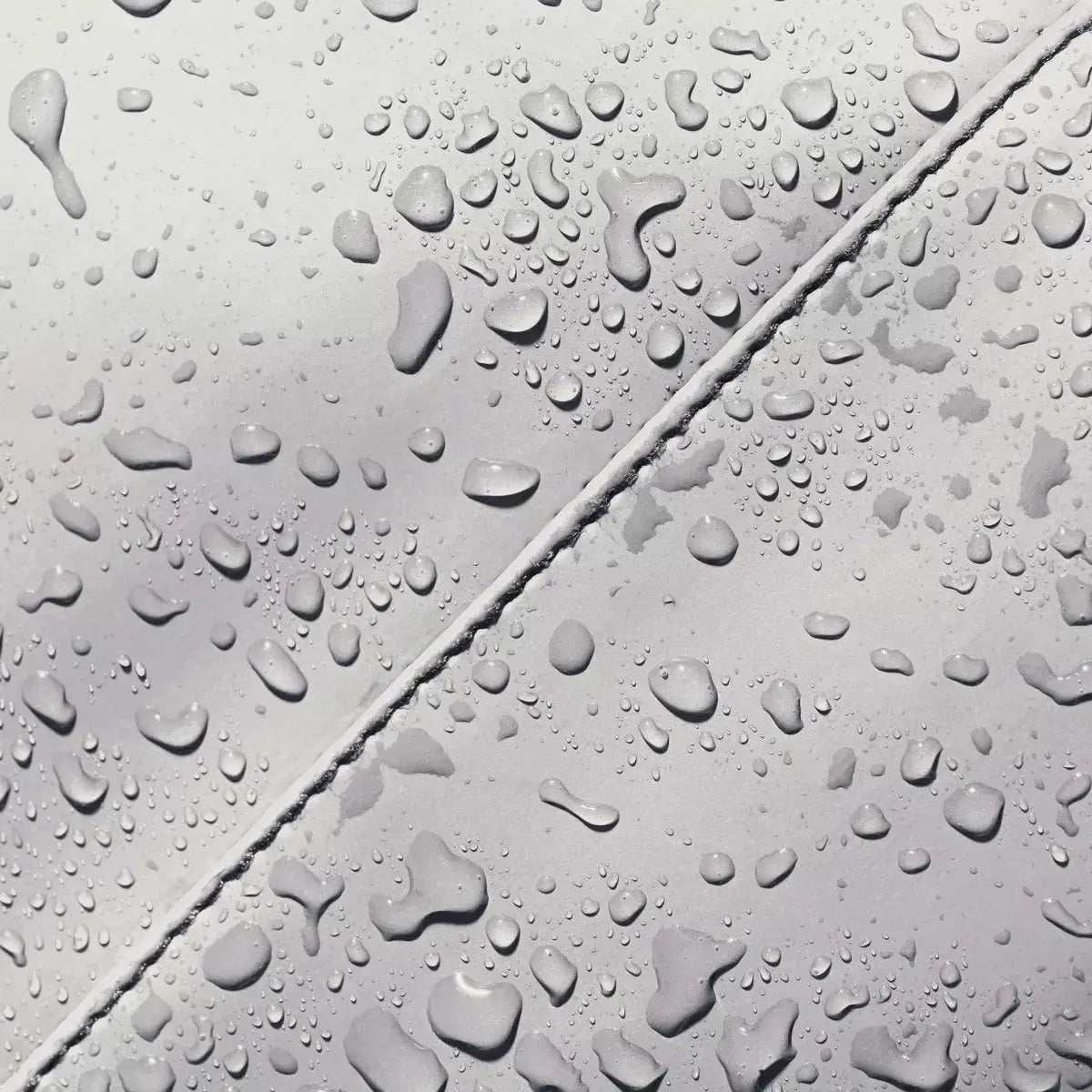 Droplets of water on a waterproof surface of Adina Mini Lotus Infinity Glacier Grey Backpack, showcasing its durability.