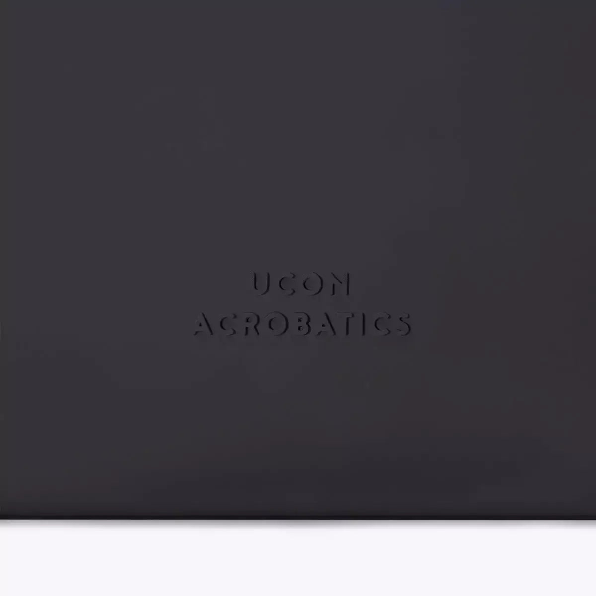 Close-up of UCON Acrobatics logo on a sleek black bag design.