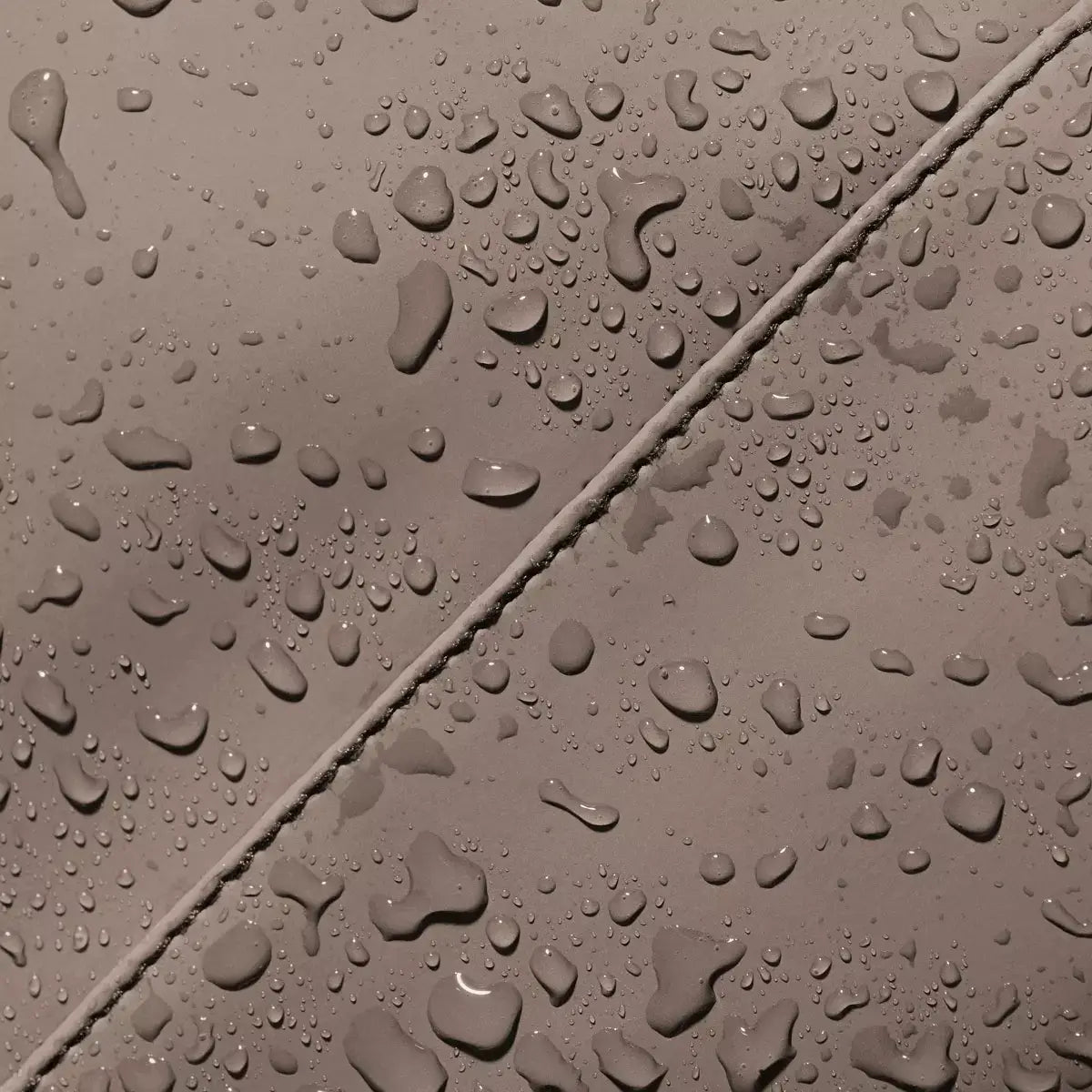 Close-up of water droplets on the Alva Medium Lotus Infinity Dark Sand Shoulder Bag's waterproof material.