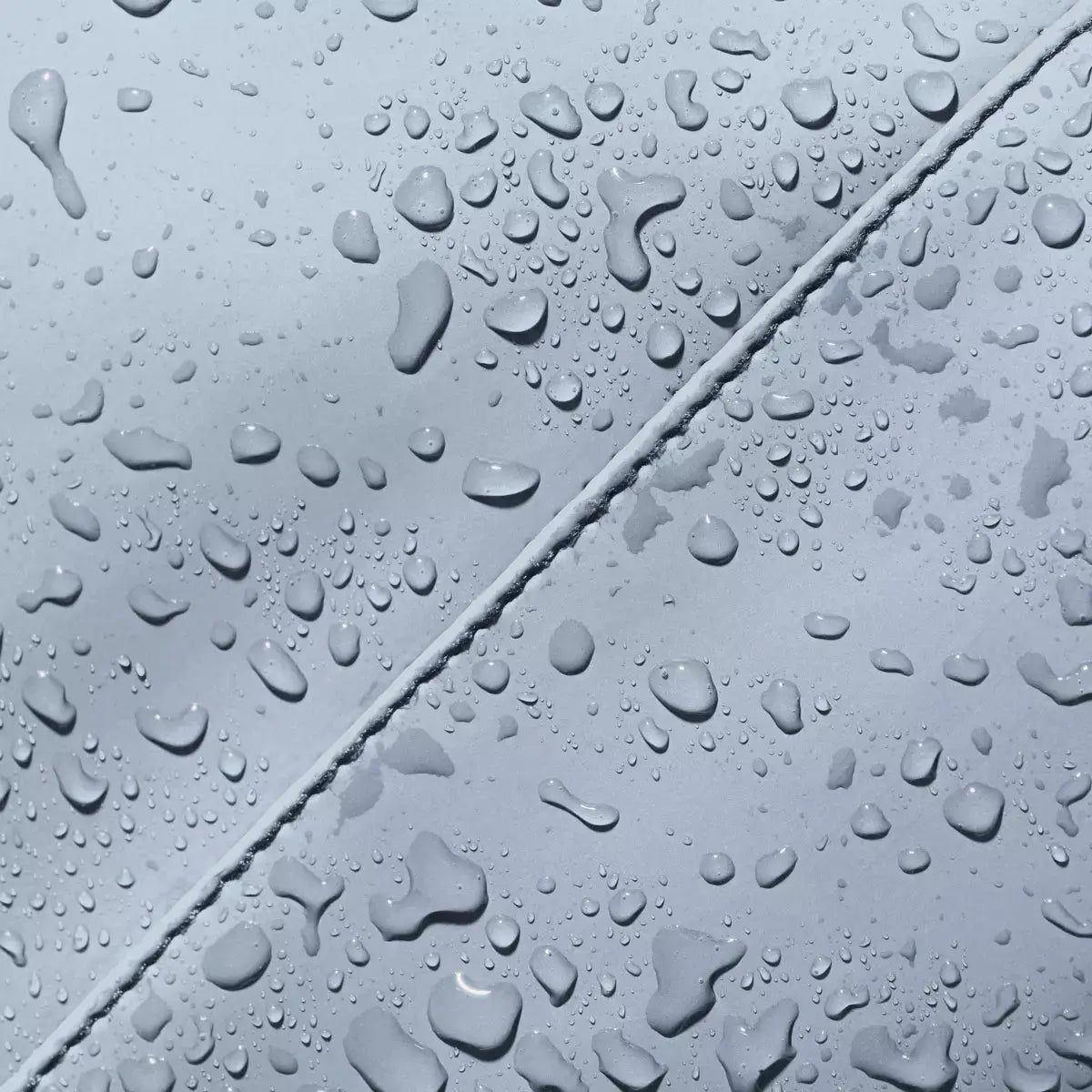 Close-up of water droplets on waterproof material, showcasing durability and water resistance of Alva Medium Lotus Infinity Fog Blue Shoulder Bag.