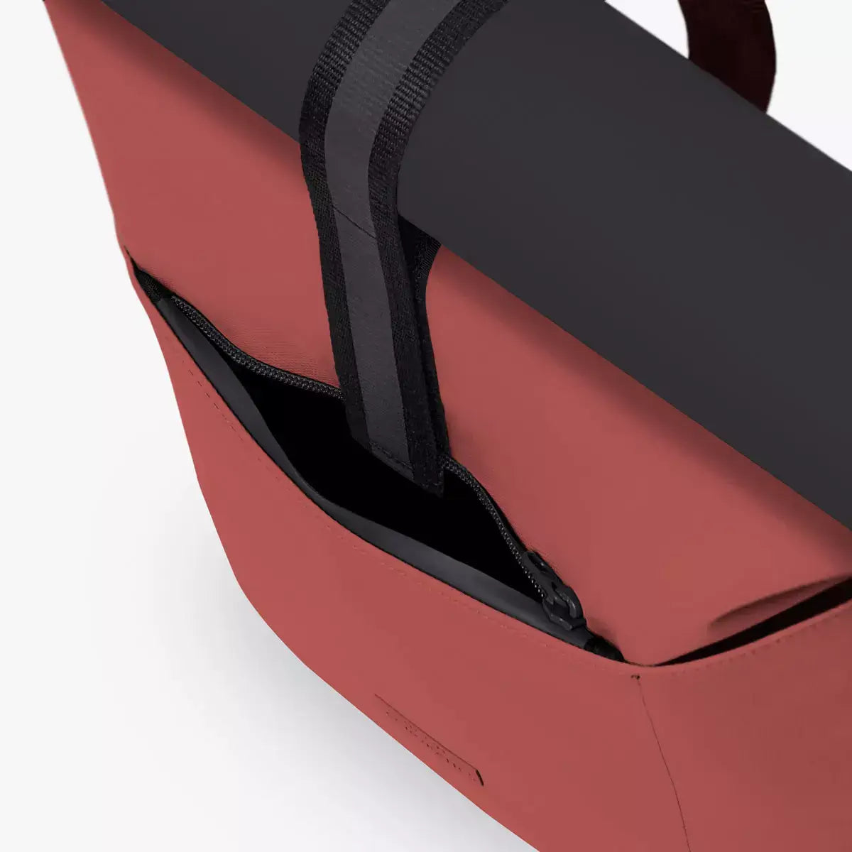 Close-up view of the Hajo Aloe Hibiscus Black Backpack showing the roll-top closure and side zipper.