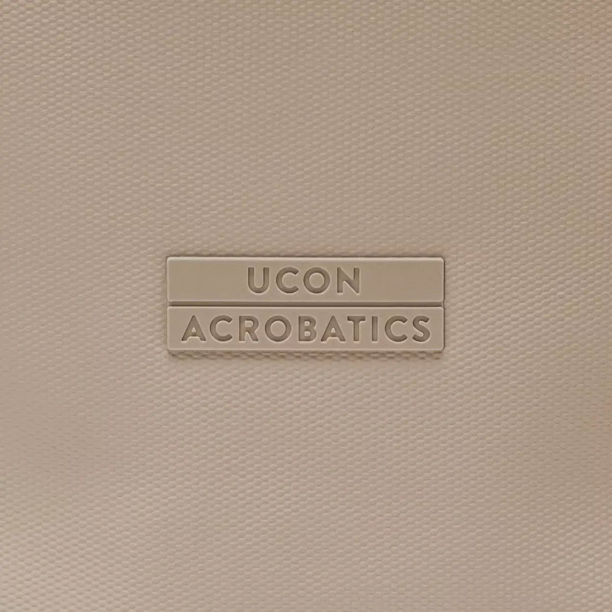 UCON Acrobatics logo on a textured light pink background, showcasing stylish and modern design aesthetics.