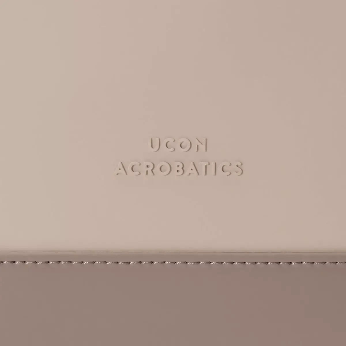 Close-up of UCON Acrobatics logo embossed on a beige material.