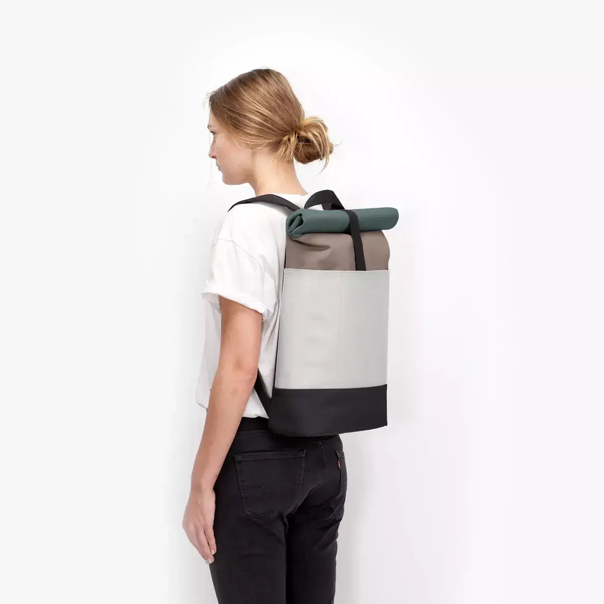 Hajo Lotus Infinity Dark Sand Glacier Grey Backpack being worn by a model from the side view.