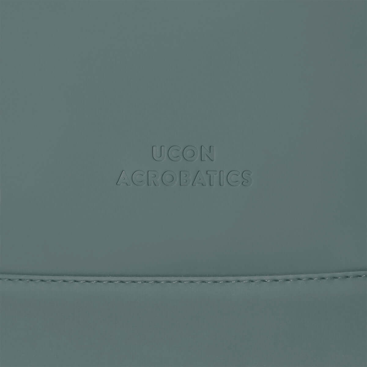 Close-up of the UCON ACROBATICS logo on a stylish gray backpack.