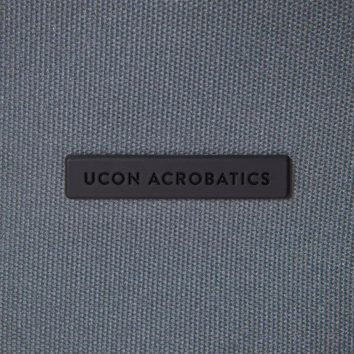 UCON ACROBATICS logo on a gray fabric background.