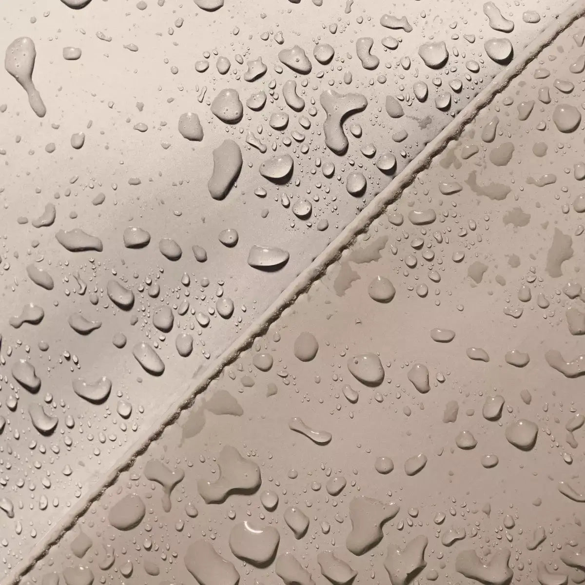 Close-up of water droplets on a waterproof surface, showcasing durability of Hajo Mini Lotus Infinity Light Sand Sand Backpack.