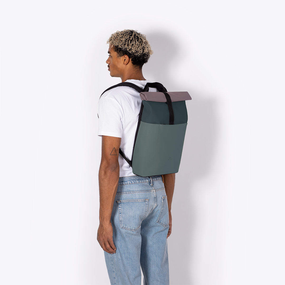Hajo Mini Lotus Forest Pine Green Backpack worn by a model, showcasing its roll-top closure and padded straps.