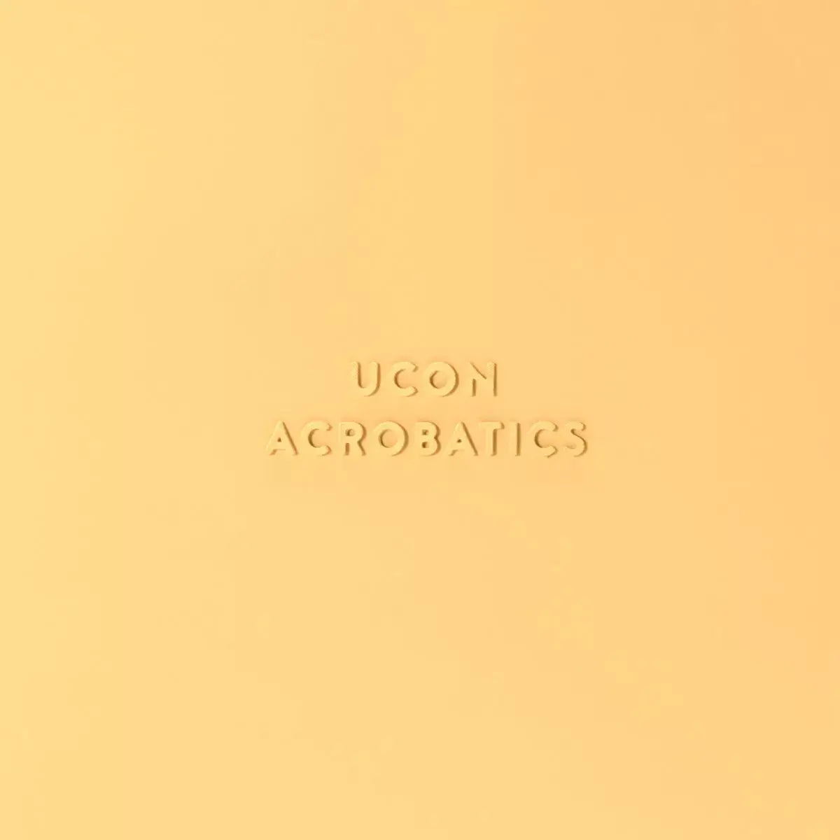 Logo of UCON Acrobatics in embossed design on a bright yellow background.