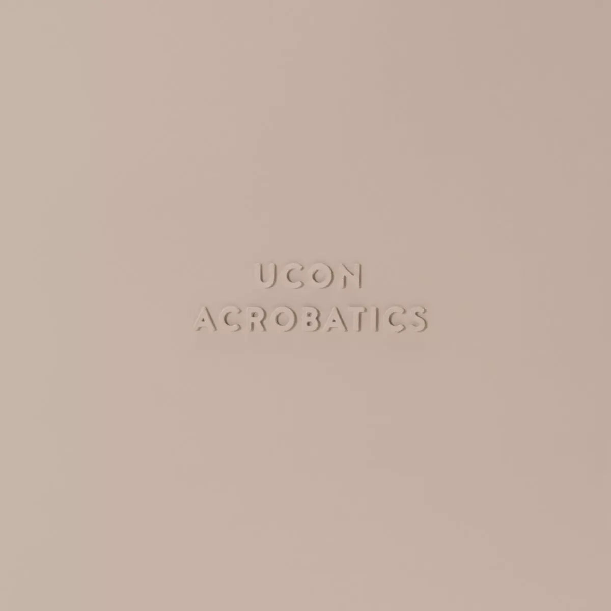 Ucon Acrobatics logo embossed on a soft beige background.