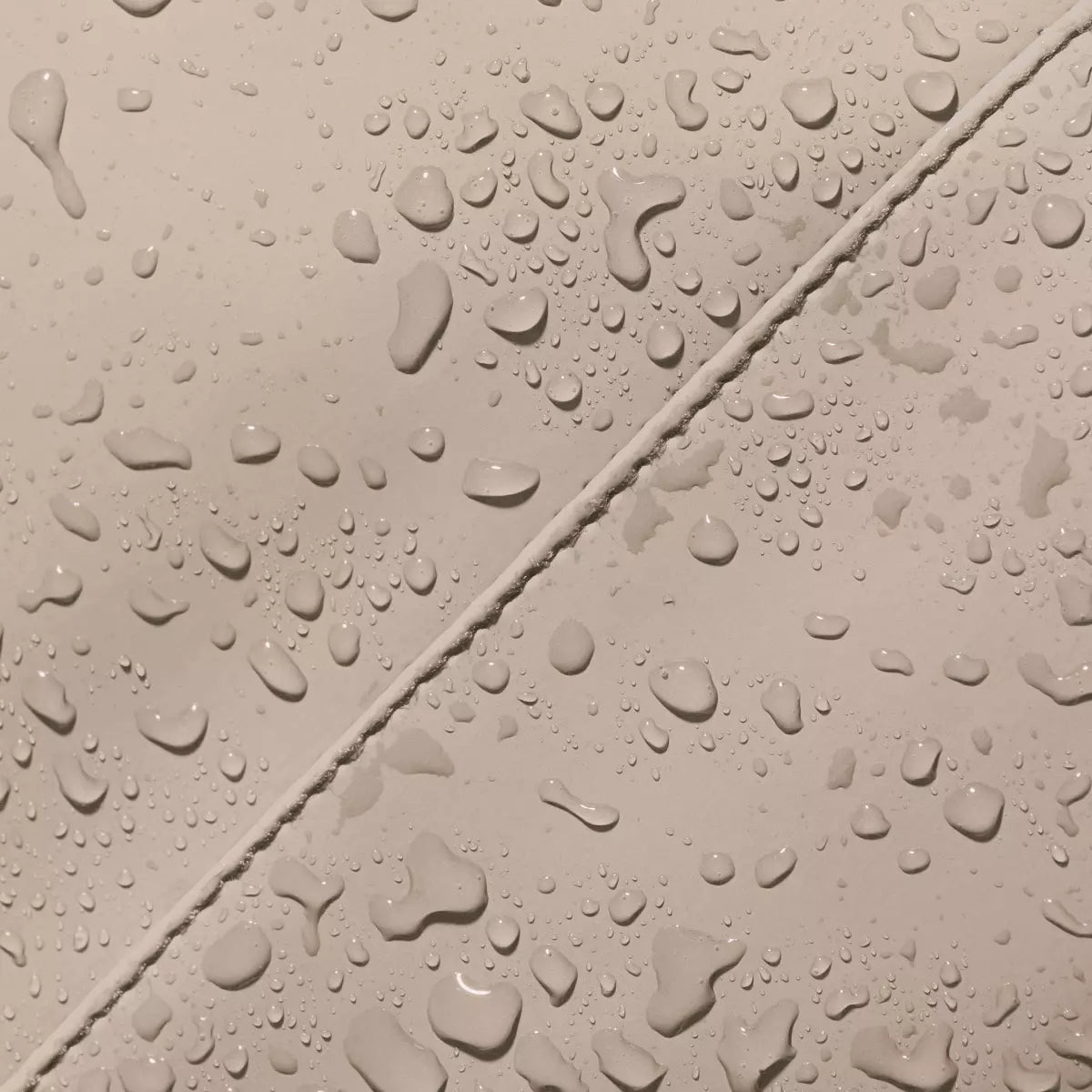 Waterproof surface detail of Hajo Mini Lotus Infinity Sand Backpack showcasing durability with water droplets.