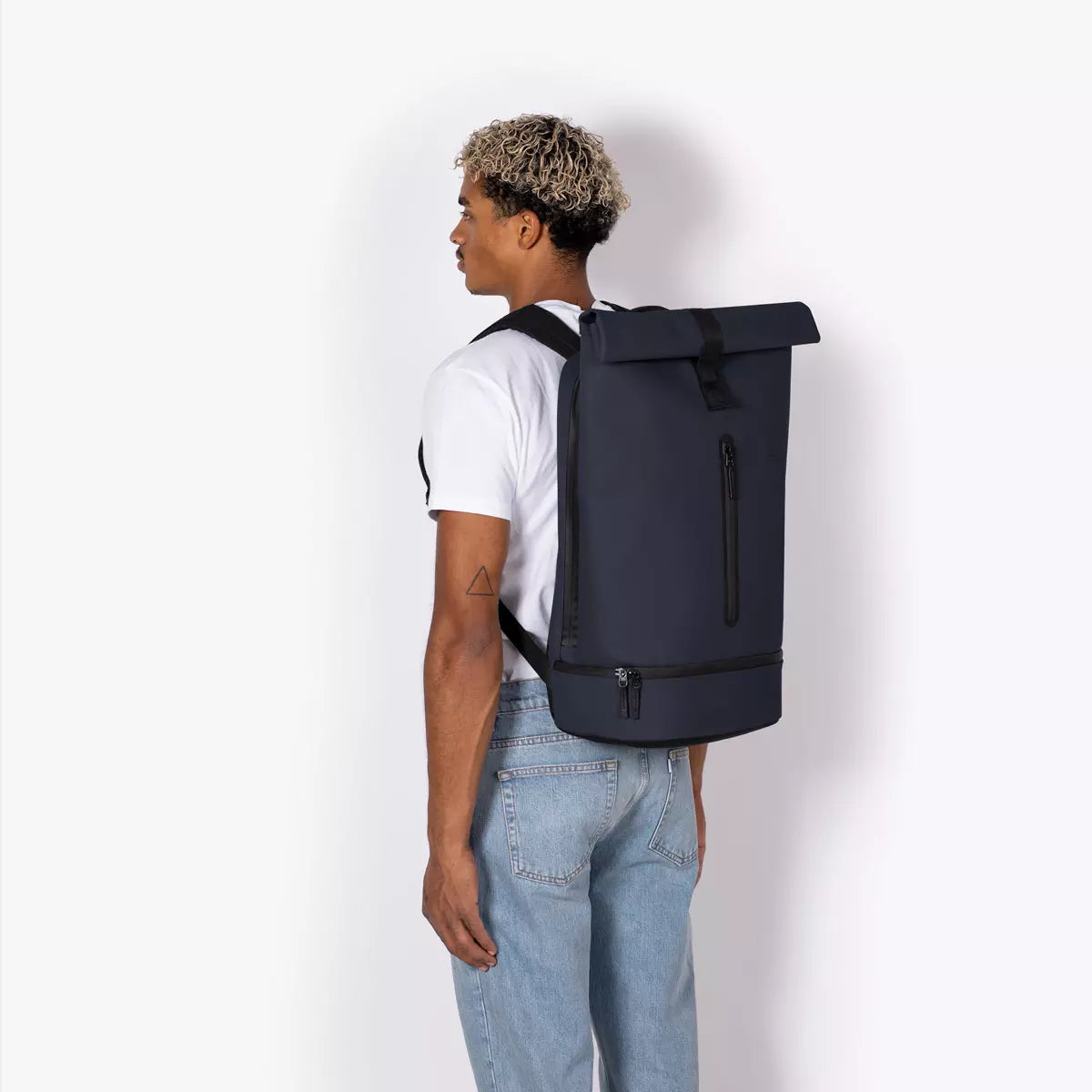 Hajo Pro Lotus Dark Navy Backpack worn by a model standing sideways, showcasing its roll-top and waterproof design.
