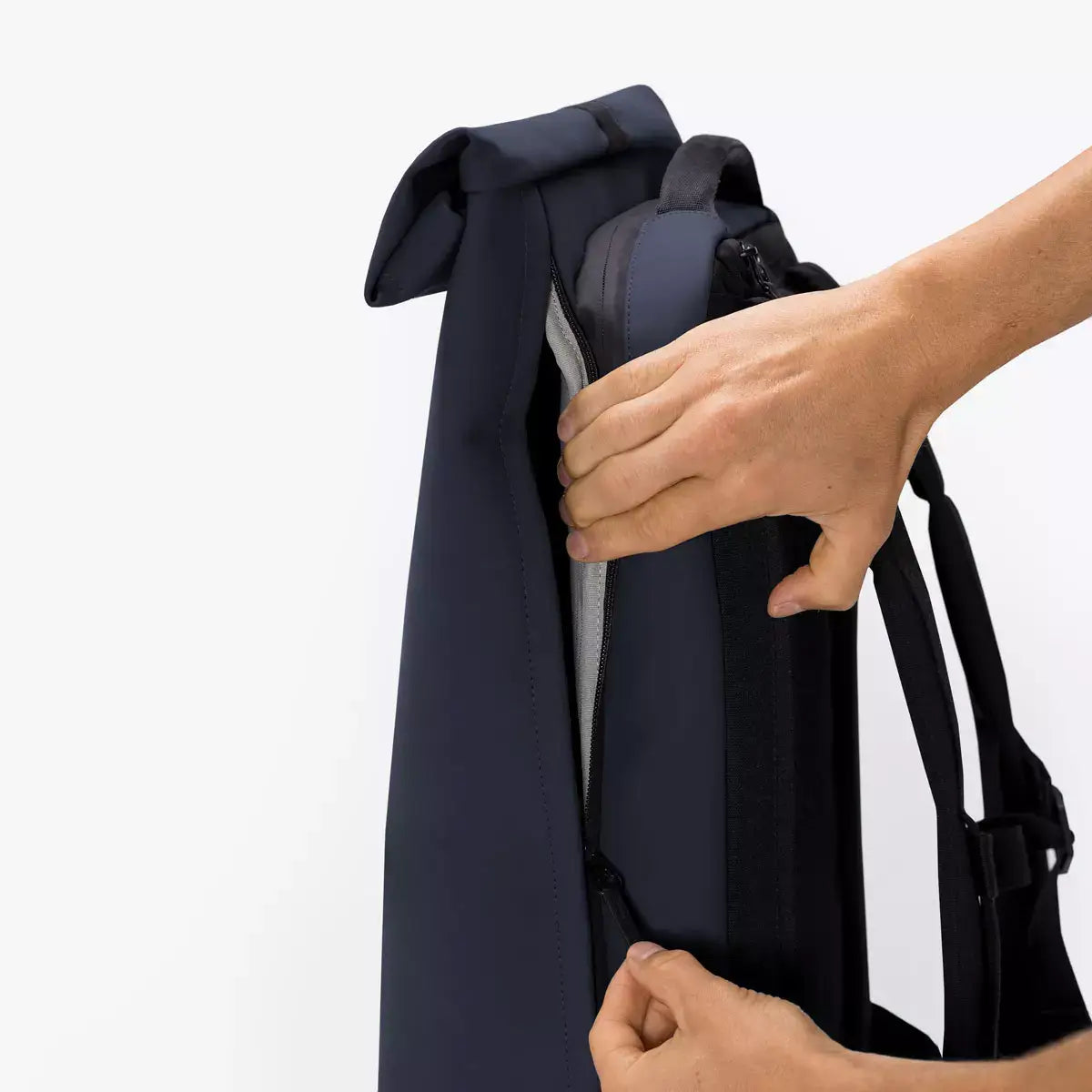 User demonstrating the roll-top closure feature of the Hajo Pro Lotus Dark Navy Backpack.