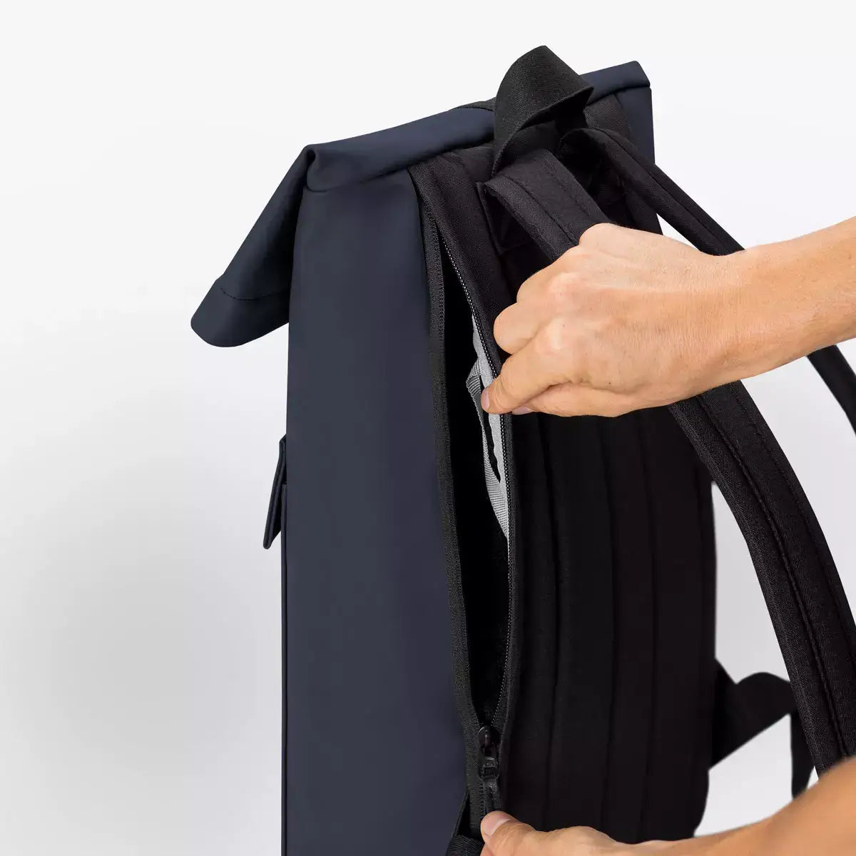 Person using the side zipper of the Jannik Medium Lotus Infinity Dark Navy Backpack.