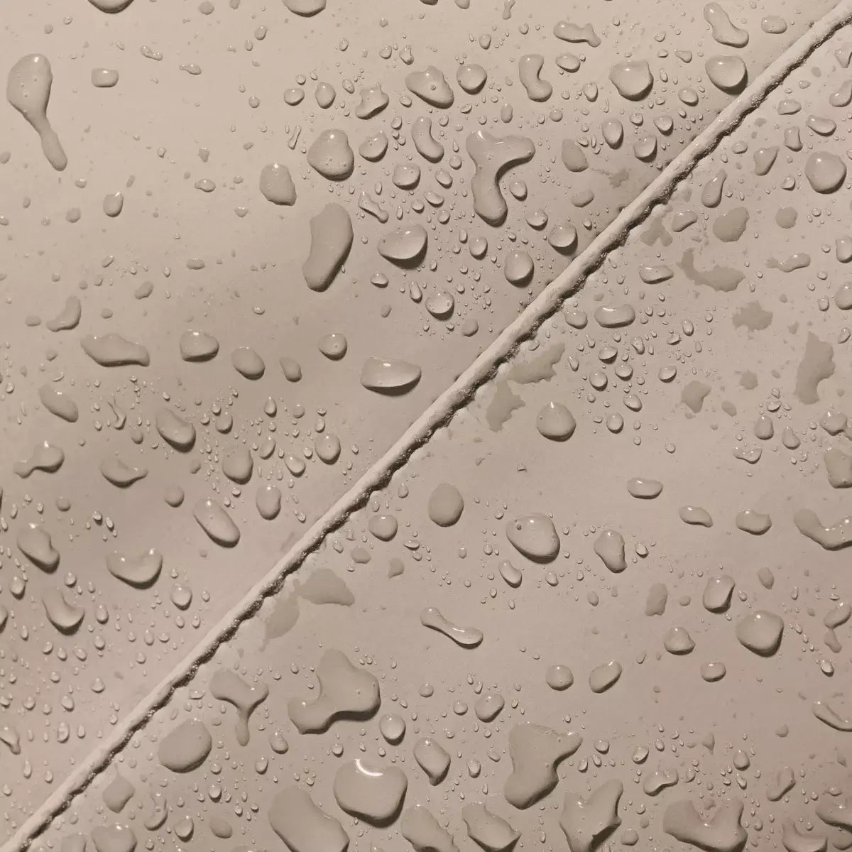 Close-up of water droplets on the Jannik Medium Lotus Infinity Sand Backpack, showcasing its waterproof features.