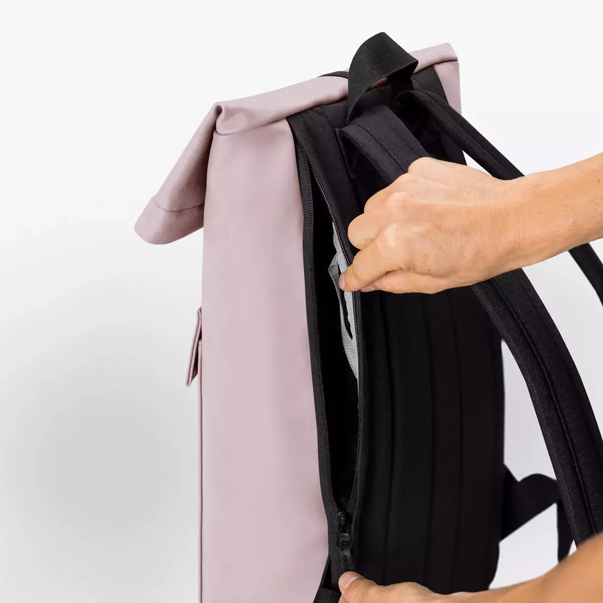 Person opening side zipper of Jannik Mini Lotus Infinity Light Rose Backpack.