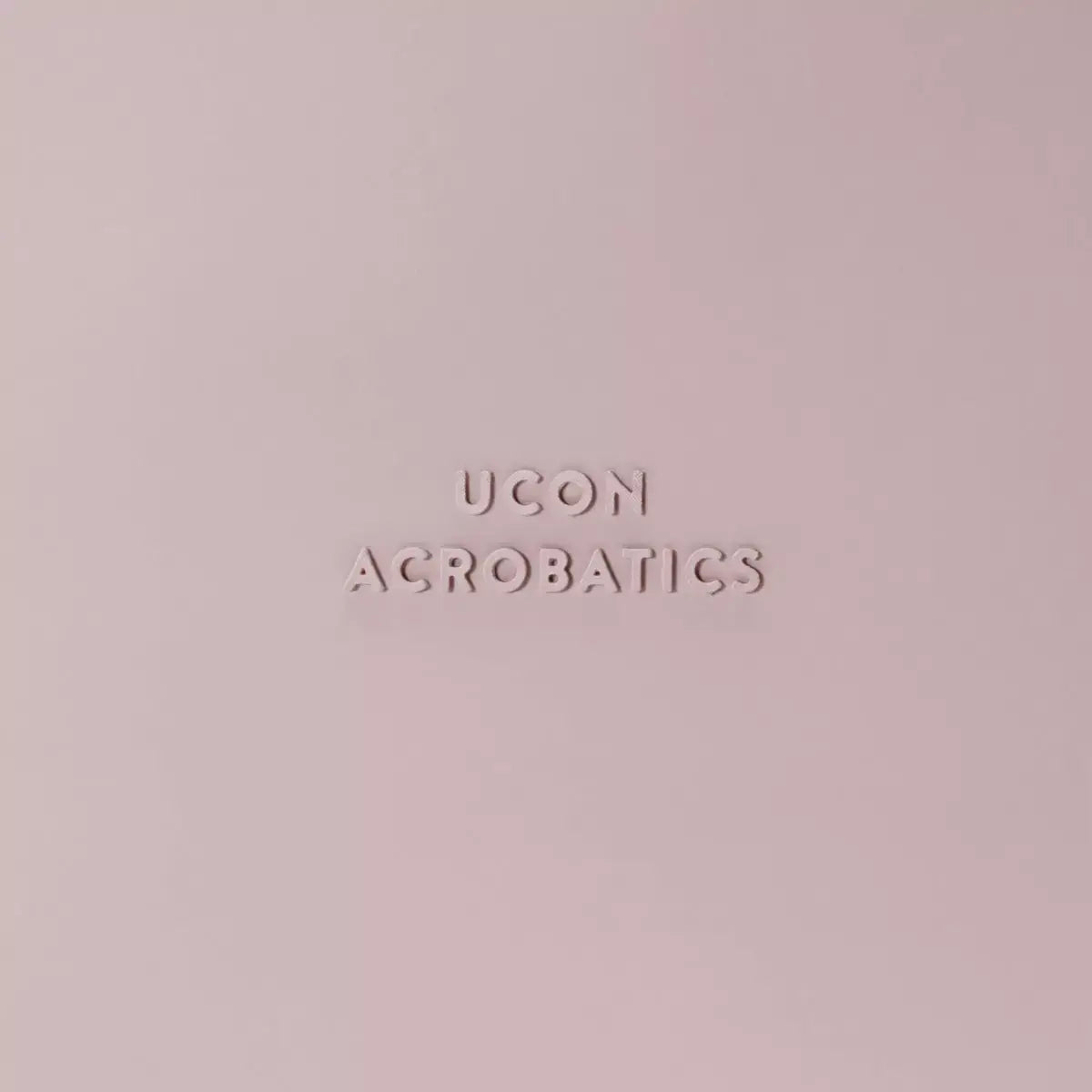UCON acrobatics logo embossed on a soft pink background in minimalistic design.