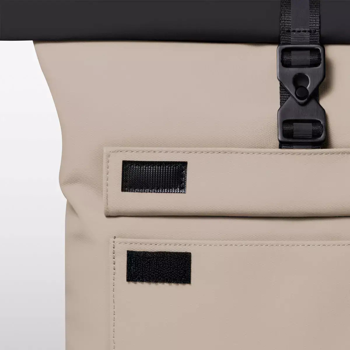Close-up of the Jasper Aloe Sand Black Backpack's roll-top closure and straps.