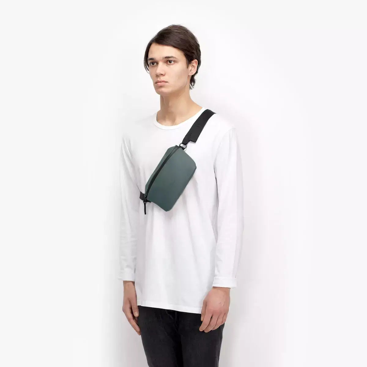 Jona Lotus Infinity Pine Green Bum Bag worn by a model in a white shirt, showcasing its stylish design.