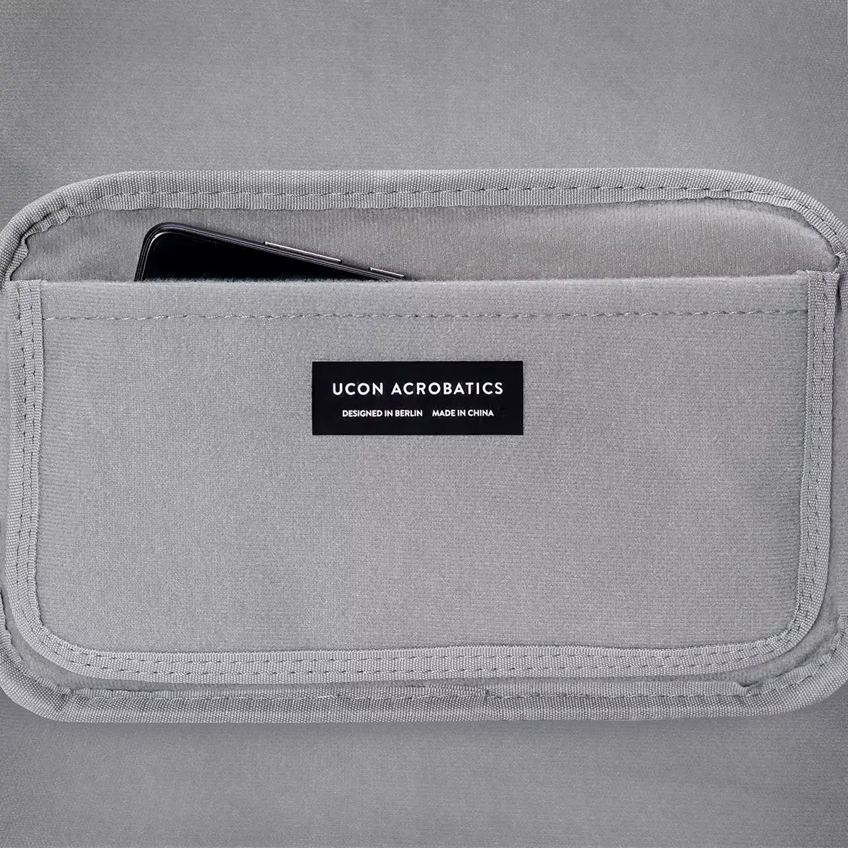 Detail view of UCON ACROBATICS bag pocket with smartphone, showcasing design and functionality.