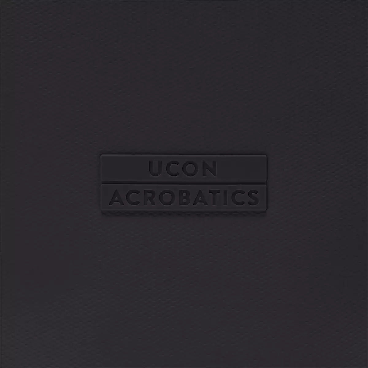 UCON Acrobatics logo embossed on a textured black background, showcasing minimalist design.