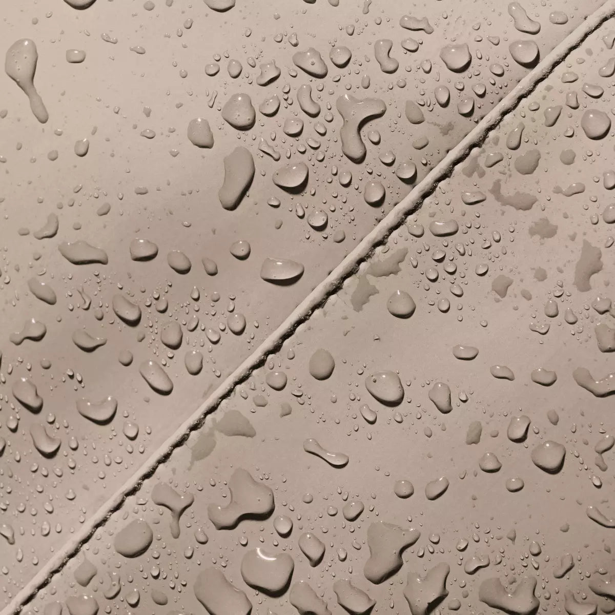 Close-up of waterproof material with water droplets, showcasing the durability of the Jona Lotus Infinity Sand Bum Bag.