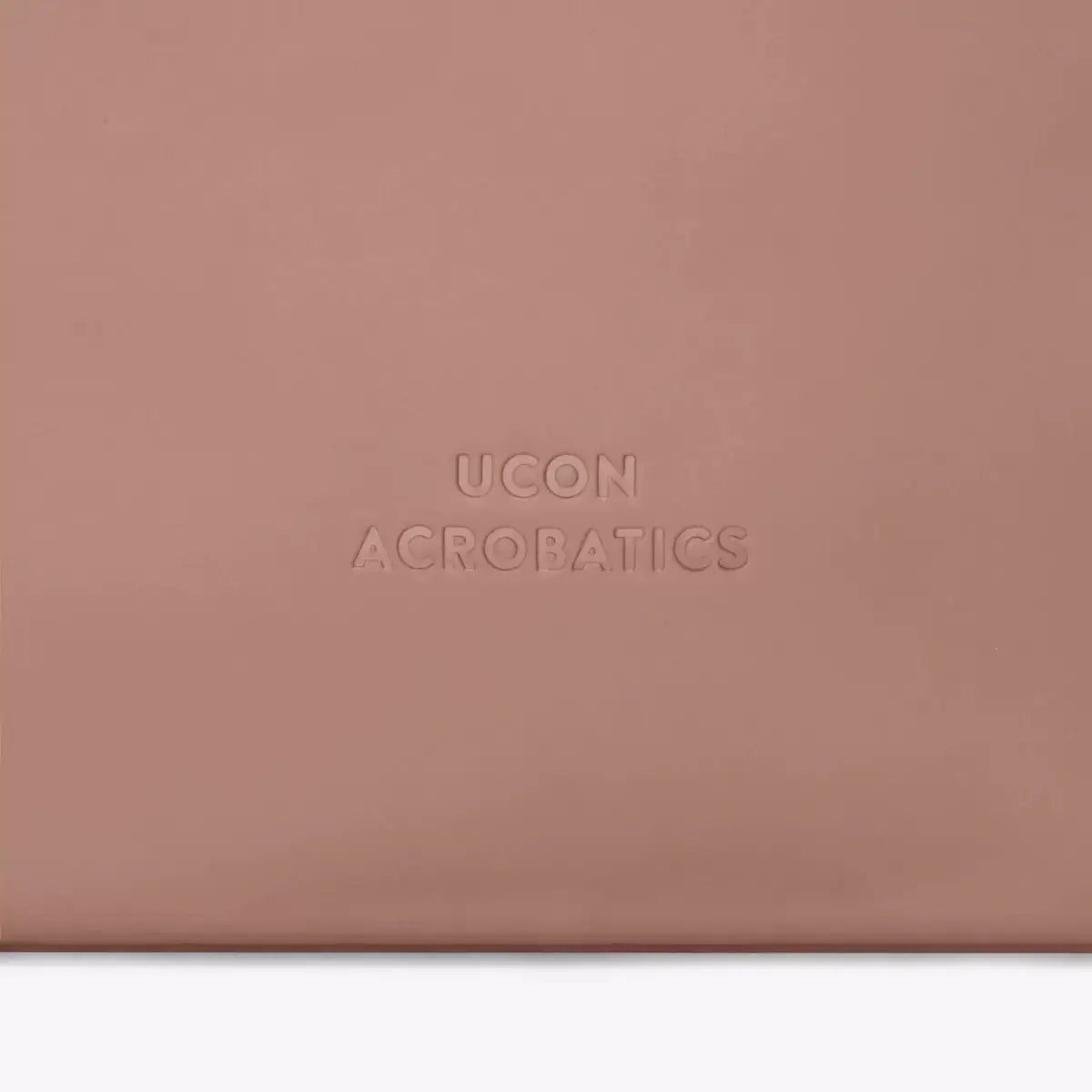 Detail shot of UCON ACROBATICS logo embossed on a soft, textured surface.