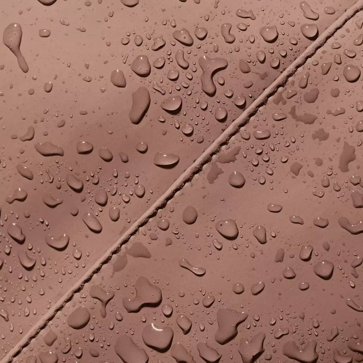 Close-up of water droplets on the Jona Lotus Redwood Bum Bag's waterproof material.